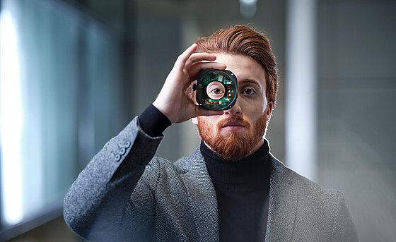  A closeup of a redhead man looking through a camera lens